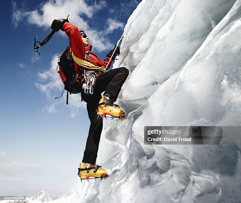 Male mountain climber on ice-covered rock face, low angle view