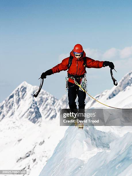 male mountain climber walking along ridge, arms outstretched - gebirgskamm stock-fotos und bilder