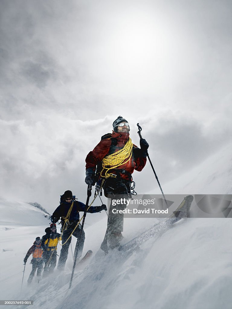 Mountain climbers walking through blizzard, linked together with rope