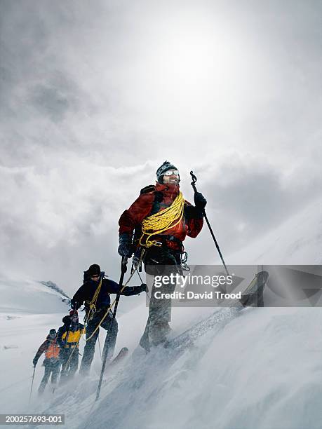 mountain climbers walking through blizzard, linked together with rope - extreme sports team stock pictures, royalty-free photos & images