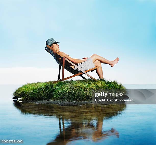 man sleeping in deckchair on grass island, side view - the castaway ストックフォトと画像