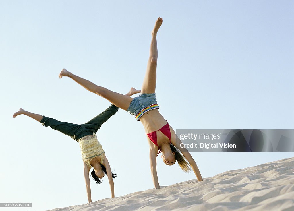 Teenage girl (13-15) and woman doing cartwheels outdoors