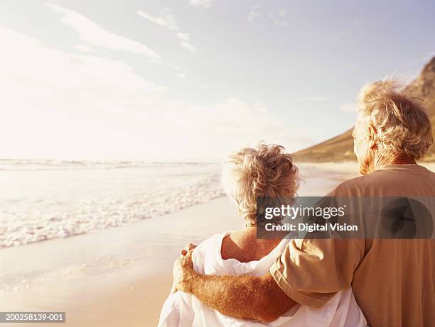 senior couple embracing on beach, rear view - senioren spazieren sommer stock-fotos und bilder