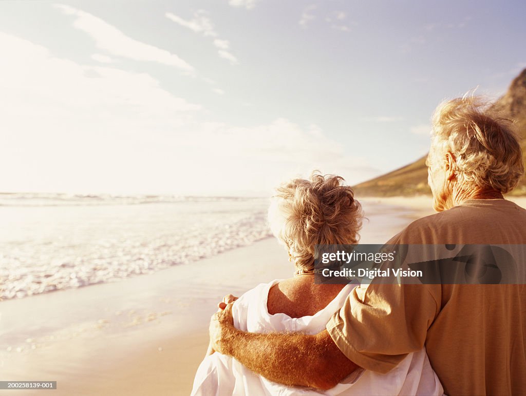 Senior couple embracing on beach, rear view