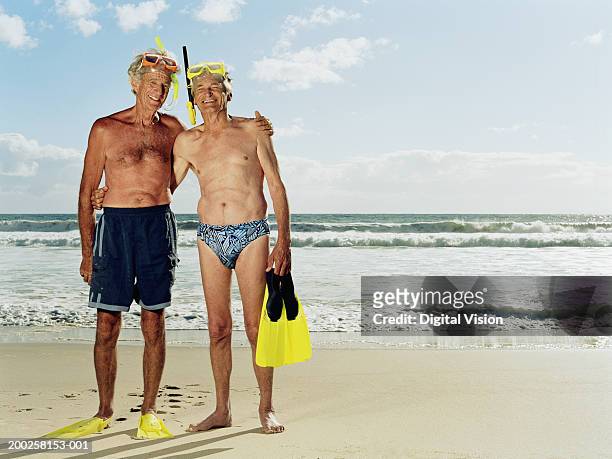 two senior men on beach, snorkle masks on head, smiling, portrait - slip de bain de compétition photos et images de collection