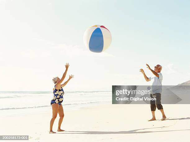 senior couple throwing beach ball on beach - man with big balls stock pictures, royalty-free photos & images