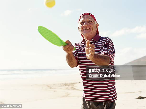 senior man playing beach tennis, smiling - andersherum stock-fotos und bilder