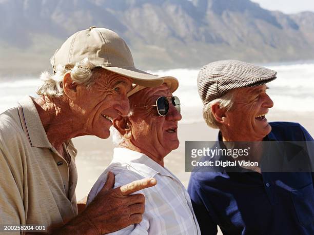 three senior men standing on beach, talking, close-up - alleen seniore mannen stockfoto's en -beelden