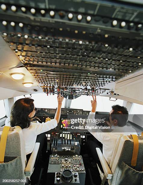 male and female aeroplane pilot, operating controls, rear view - navigator foto e immagini stock