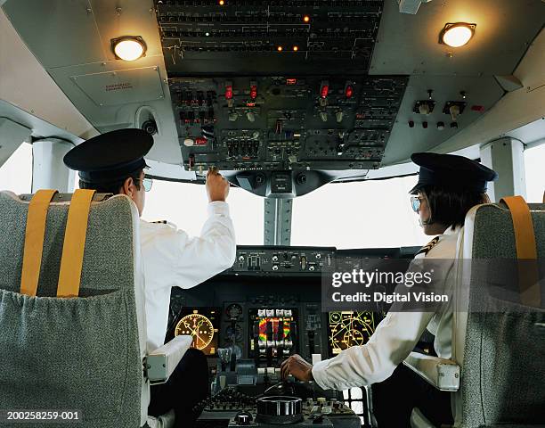 male and female aeroplane pilot, operating controls, rear view - kopilot stock-fotos und bilder