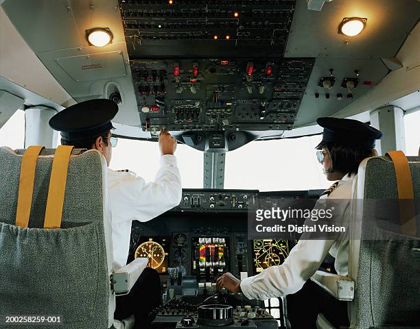 male and female aeroplane pilot, operating controls, rear view - airline pilot imagens e fotografias de stock