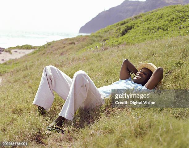 mann liegt auf gras, hände hinter dem kopf, lächelt - kailua stock-fotos und bilder