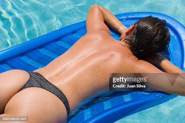 woman lying on raft in pool, rear view - sunbathing stockfoto's en -beelden