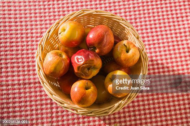 rotten apple among good ones in basket on table - fruit decay stockfoto's en -beelden