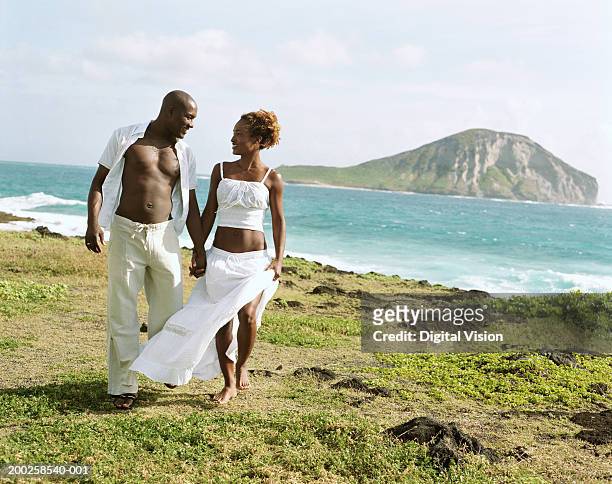 couple holding hands, walking by ocean - kailua stockfoto's en -beelden