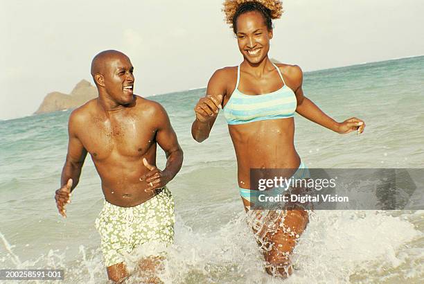 couple running in ocean, smiling - kailua stockfoto's en -beelden