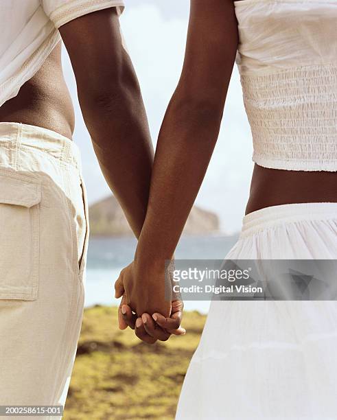 couple holding hands by ocean, close-up, rear view - kailua stockfoto's en -beelden