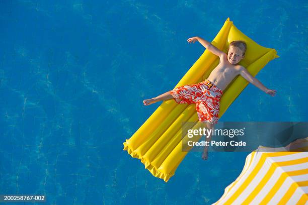 boy (8-10) lying on float in pool, elevated view - pool raft stock pictures, royalty-free photos & images