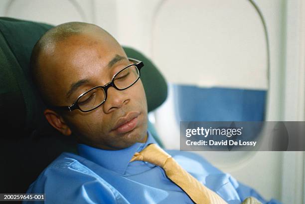 businessman sleeping in airplane - david de lossy sleep stock pictures, royalty-free photos & images