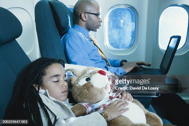 businessman on aeroplane using laptop computer by girl sleeping - david de lossy sleep stock pictures, royalty-free photos & images