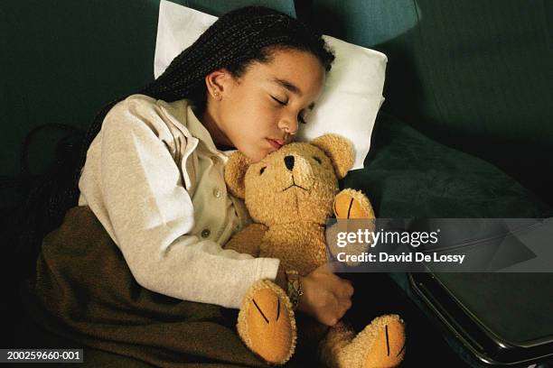 girl sleeping with stuffed animal in commercial airplane - david de lossy sleep stock pictures, royalty-free photos & images