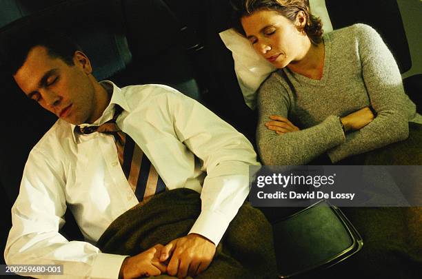 businessman and woman sleeping in airplane - jet lag stockfoto's en -beelden
