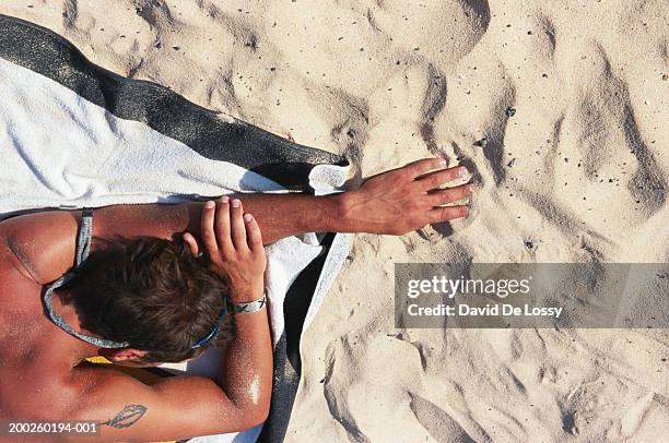 young man lying on beach, rear view - david de lossy sleep stock pictures, royalty-free photos & images