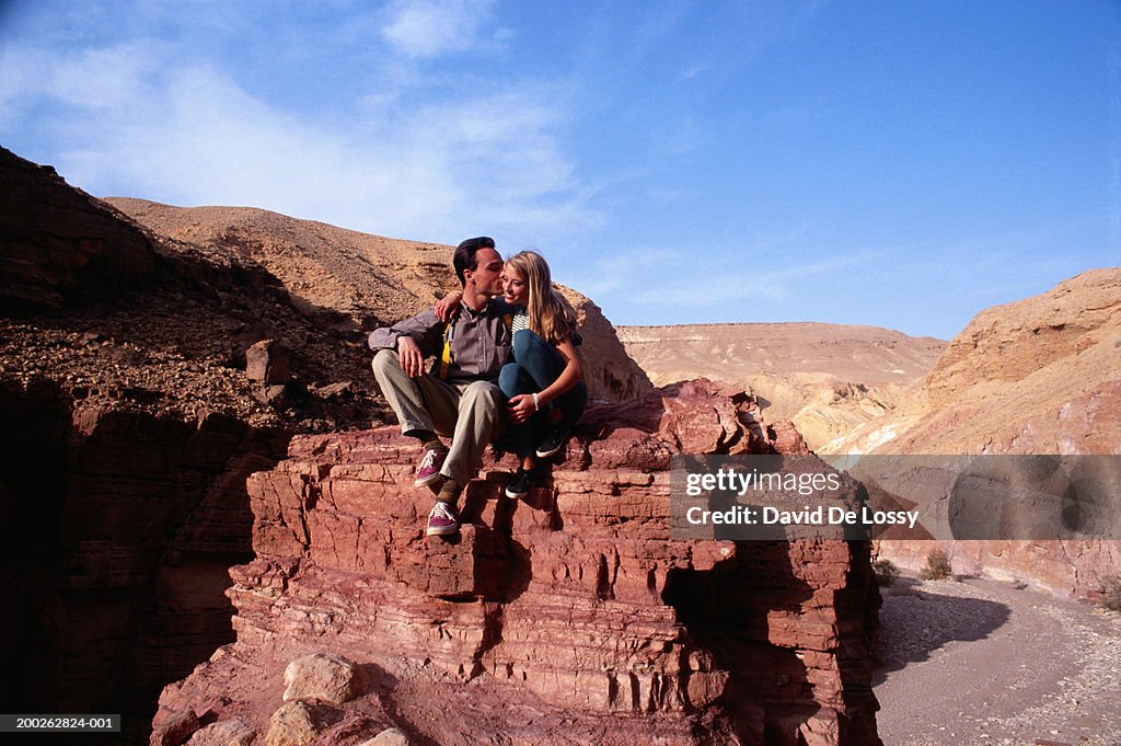 Man kissing woman on rock