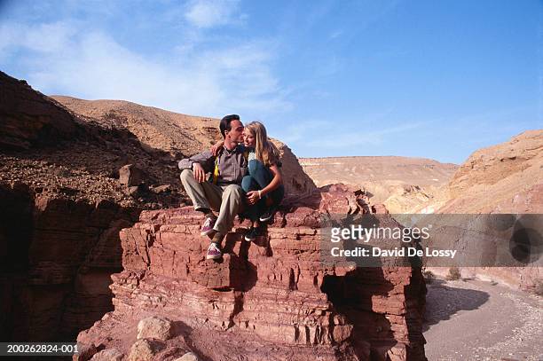man kissing woman on rock - straight black hair stock pictures, royalty-free photos & images