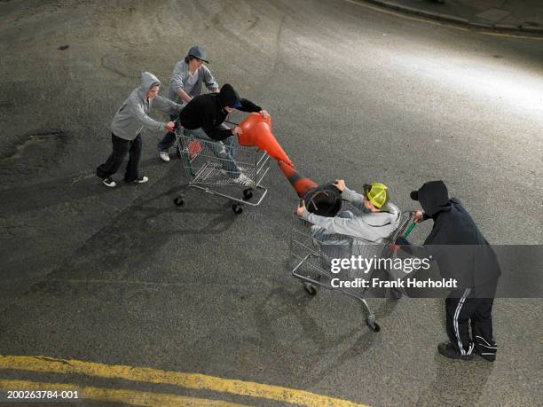 group of teenage boys (13-15) play fighting in shopping trolleys - thug boy stock pictures, royalty-free photos & images