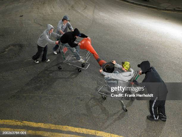 group of teenage boys (13-15) play fighting in shopping trolleys - hooligans stock pictures, royalty-free photos & images