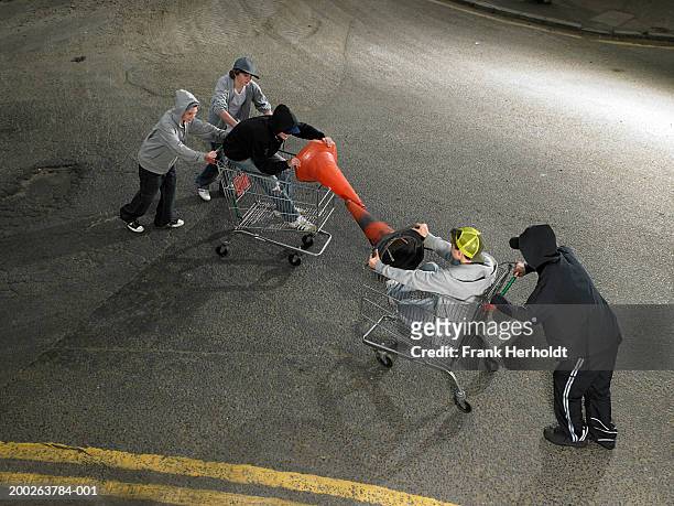 group of teenage boys (13-15) play fighting in shopping trolleys - hooligan 個照片及圖片檔