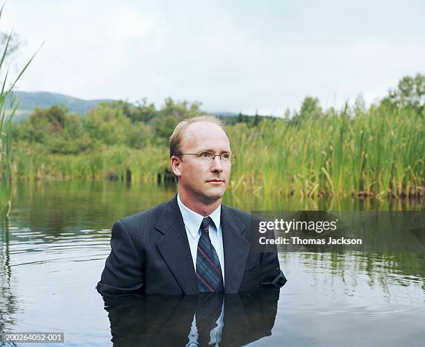 businessman standing chest deep in water - vadear imagens e fotografias de stock