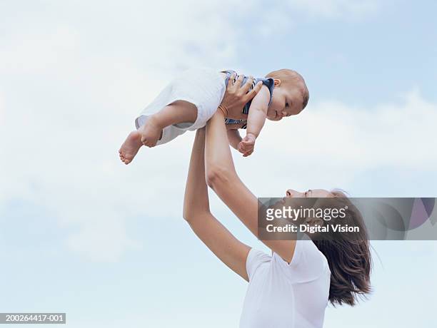 mother holding up baby boy (6-9 months), outdoors, side view - reinforcements ストックフォトと画像