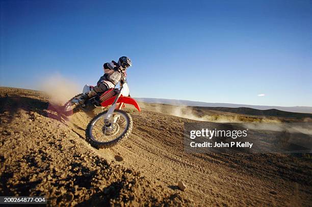 motocross driver on dirt road, side view - dirt road motorbike stock-fotos und bilder