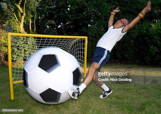 senior man kicking giant football, arms raised (blurred motion) - man with big balls stock pictures, royalty-free photos & images