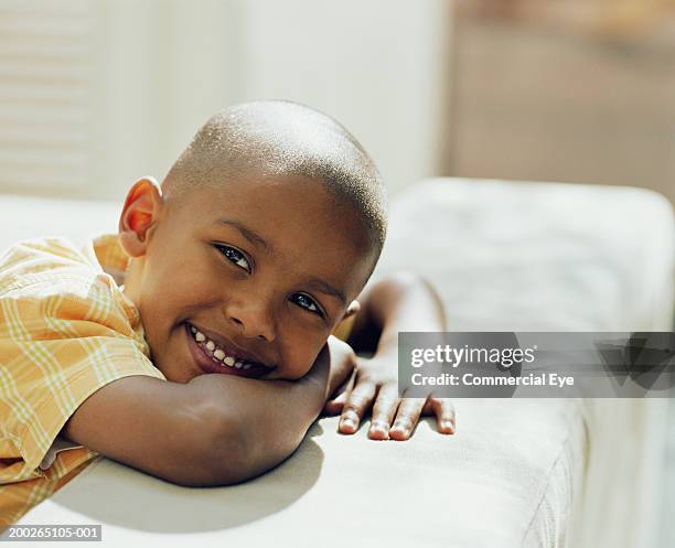 boy (5-7) leaning on sofa, portrait, close-up - boy yellow shirt stock pictures, royalty-free photos & images