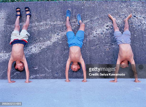 three boys (9-11) in shorts doing handstands against wall - équilibre sur les mains photos et images de collection