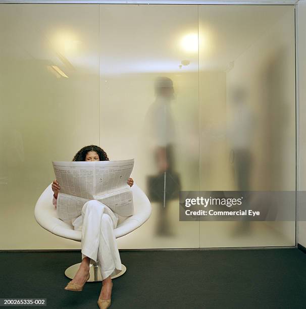 woman sitting on chair, reading newspaper, two men behind glass wall - mens black dress shoes stock pictures, royalty-free photos & images