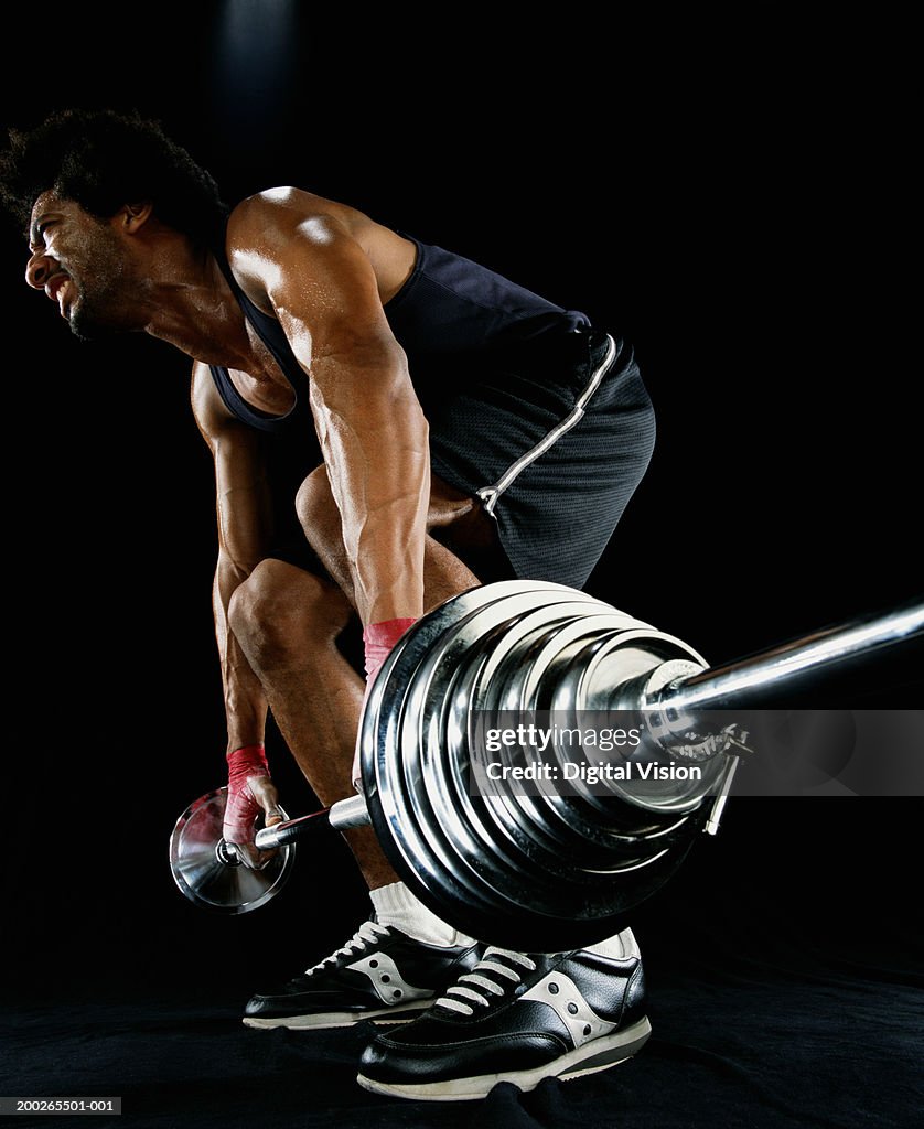 Young man lifting barbell, low angle view