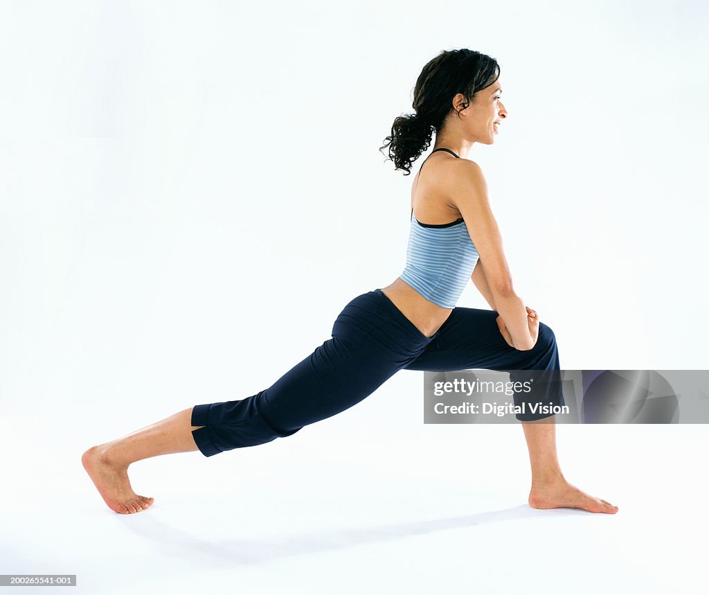 Young woman performing stretching exercise, side view