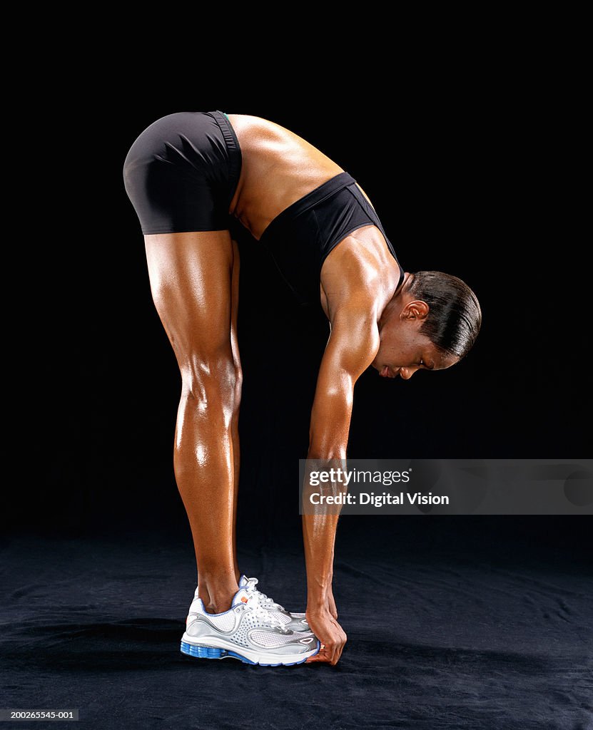 Young female runner touching toes, side view