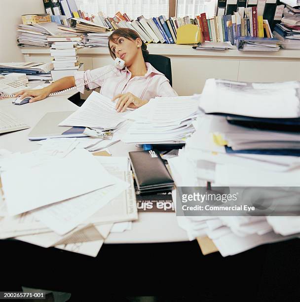 woman sitting in messy office using phone - voll geladen stock-fotos und bilder