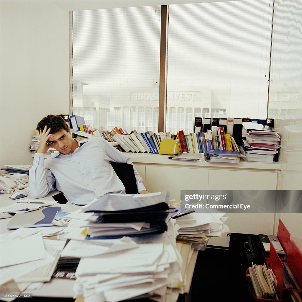 Man sitting behind messy desk (focus on man)