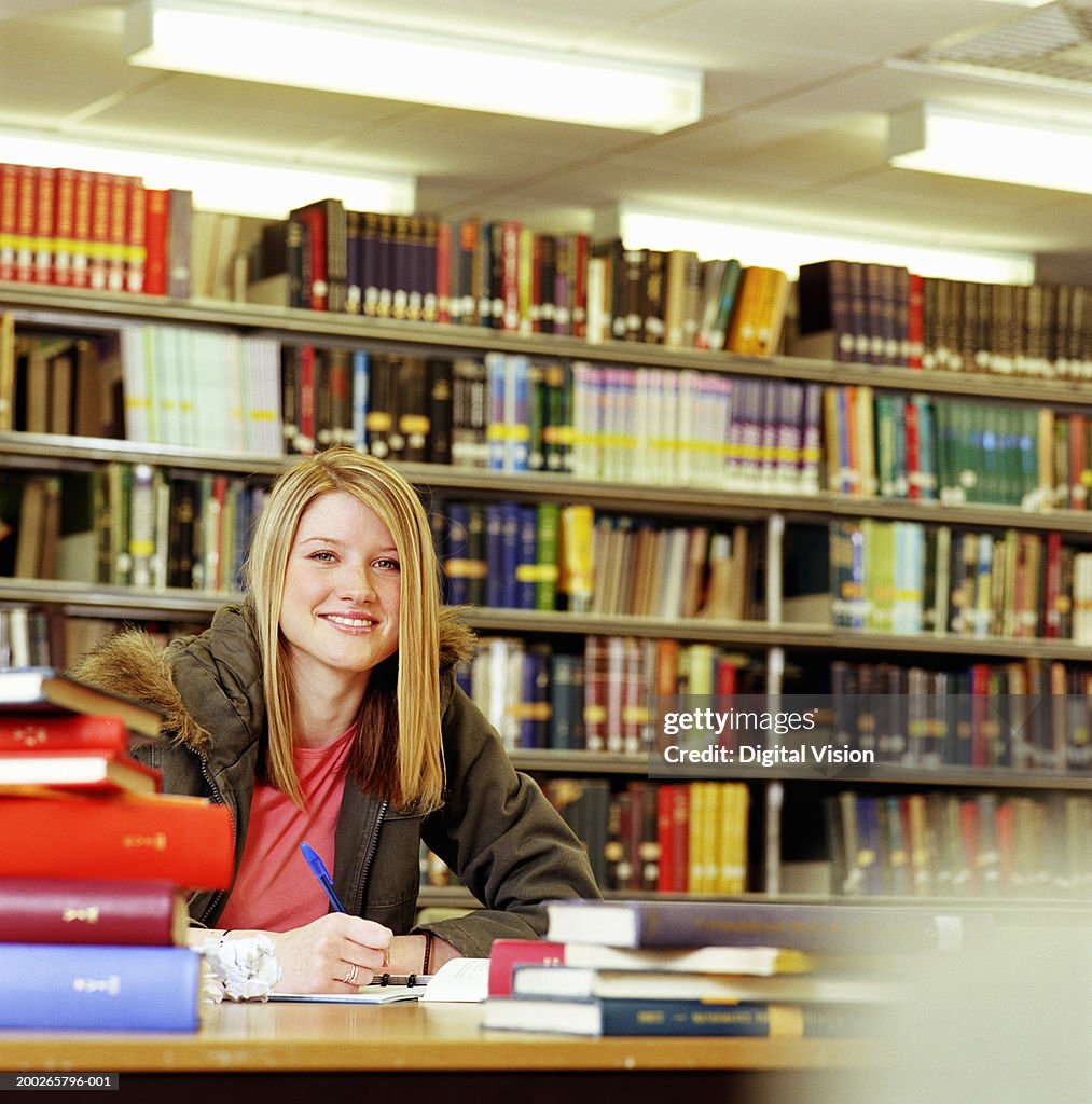 Female college student in library, smiling, portrait