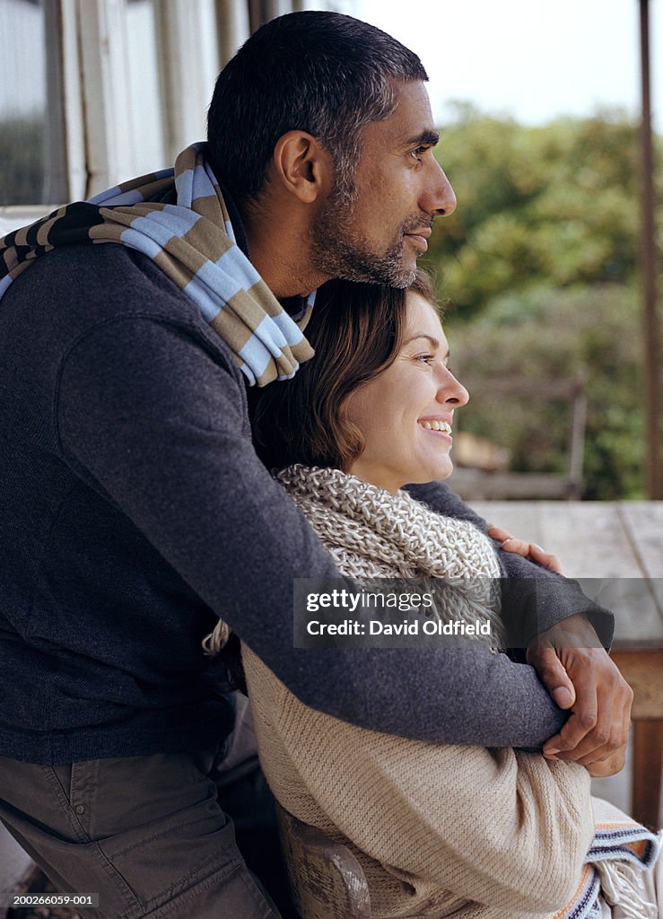 Man embracing woman outdoors, side view