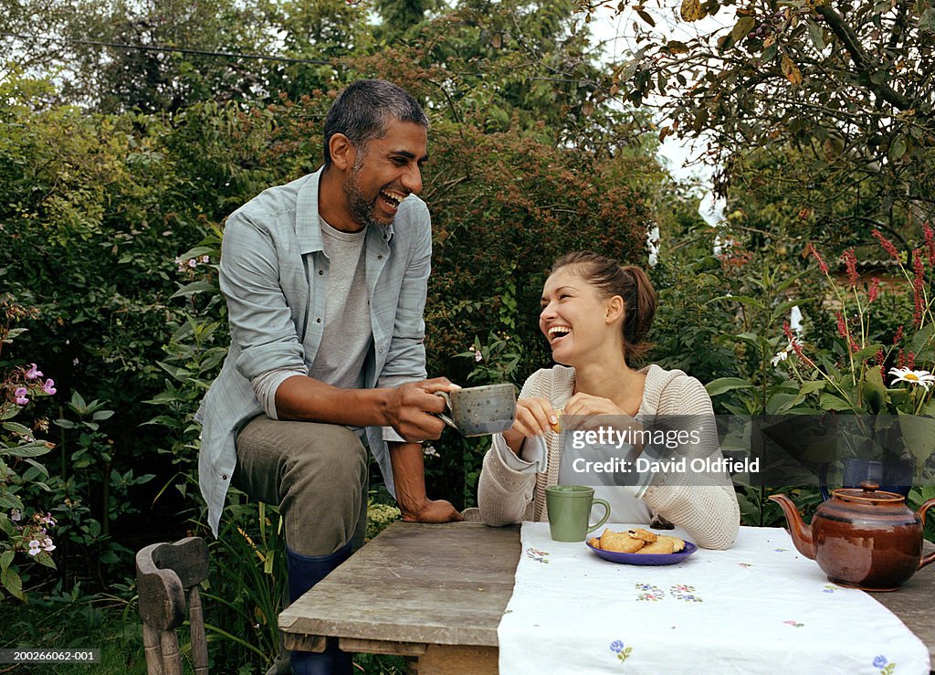 Couple having tea at garden table, laughing