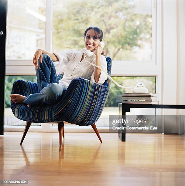 woman sitting in chair, using phone - festnetztelefon stock-fotos und bilder