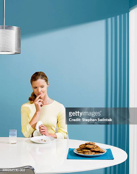 woman looking at plate of cookies - temptation stock pictures, royalty-free photos & images