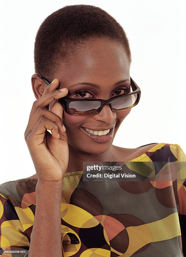 Woman looking over top of sunglasses, smiling, portrait, close-up